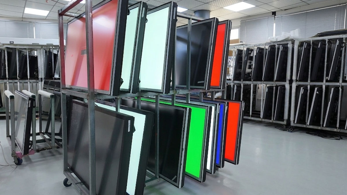 Factory staging area showing batch production of outdoor wall-mounted LCD digital signage displays prepared for quality inspection and global delivery